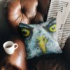 Grey and yellow owl cushion on armchair