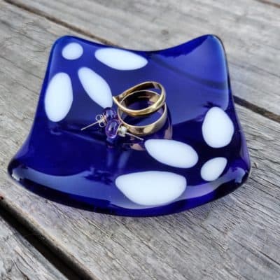 Blue and white daisy trinket dish with rings in it,sat on a table