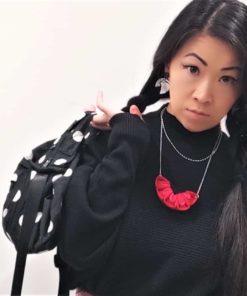 model holding a black polkadot bag wearing a red necklace