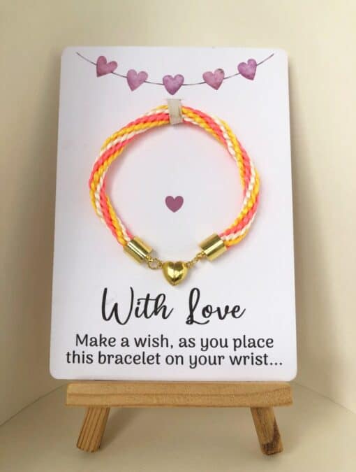 Colorful braided bracelet with a gold heart charm on a small easel. The card reads: "With Love. Make a wish, as you place this bracelet on your wrist.