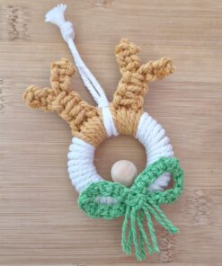 Handmade decoration with a wooden ring wrapped in white string, adorned with brown antlers and a green crocheted bow.