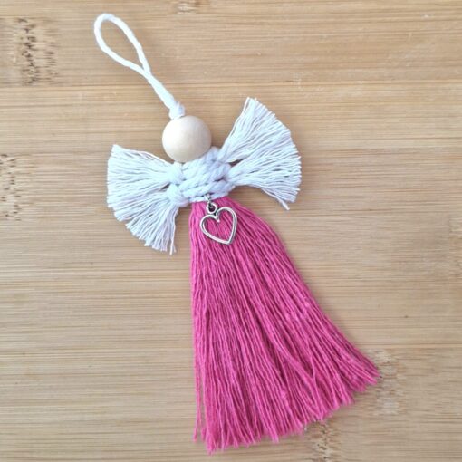 Handmade angel ornament with a wooden bead head, white yarn wings, and a pink yarn body featuring a silver heart charm.