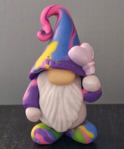 Colorful gnome figurine with a rainbow-patterned hat and beard, holding a butterfly on a dark surface.