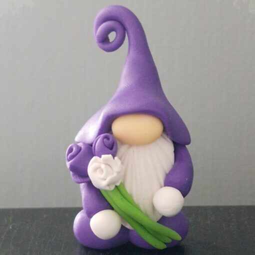 A purple clay gnome figurine holds two purple roses and one white rose, wearing a tall, curly hat.