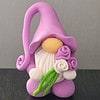 A small gnome figurine with a tall purple hat, holding a bouquet of purple and white roses on a dark background.