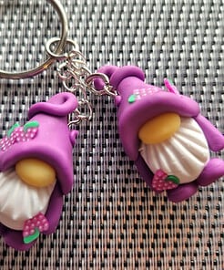 Two purple gnome keychains with white beards and yellow noses, lying on a black and white checkered surface.