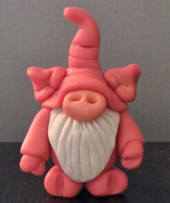 Pink clay gnome with a tall hat, large nose, and white beard, standing against a gray background.