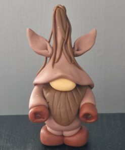 Clay figurine resembling a gnome with a tall hat, large ears, brown outfit, and beard on a black surface against a gray background.