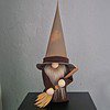 Gnome figure with long gray beard, brown robe, tall pointed hat, and holding a wooden broom, standing on a black surface.