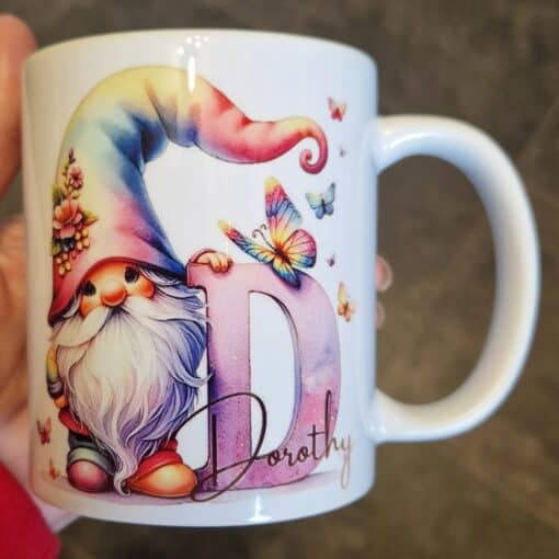 Mug featuring a colorful gnome with a rainbow hat, large letter "D," butterflies, and the name "Dorothy.