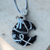 A necklace with a pendant featuring a small astronaut figure on a wire-wrapped black stone, resembling the shape of a crescent moon.