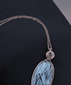 Pendant with an oval blue gemstone and delicate black streaks, wrapped in copper wire, on a matching copper chain.