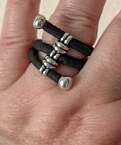 A hand wearing a ring made of three parallel black bands with silver beads and end caps.