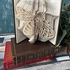 Open book with intricately folded pages forming a butterfly design, placed on top of two closed books on a wooden surface.