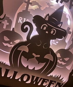 Silhouette of a black cat wearing a witch hat sitting on a jack-o'-lantern with 