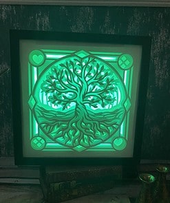 Glowing green framed artwork depicting a tree with roots, illuminated against a textured dark wall.