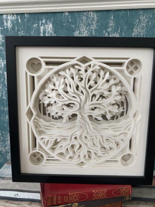 Framed 3D paper art of a tree of life with intricate roots and branches, set against a teal textured wall.