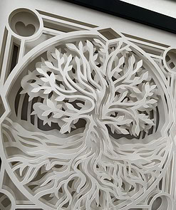 Intricate white paper cut-out depicting a stylized tree with roots, framed in geometric shapes.