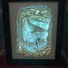 Framed illuminated artwork of an underwater scene with a whale, mermaid, coral, and jellyfish, glowing in blue tones.