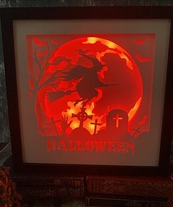 Glowing Halloween artwork features a witch on a broomstick, graveyard, bats, and a red moon with 