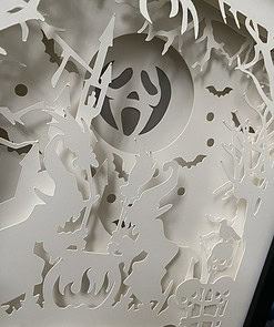 Intricate Halloween-themed paper cutout with witches, cauldron, ghosts, bats, and spooky trees under a full moon.