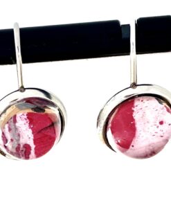 Round pink and white gemstone earrings with silver frames, hanging on a horizontal black rod.