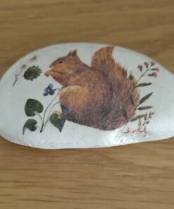 Smooth white stone with a painted image of a brown squirrel surrounded by green leaves and purple flowers.