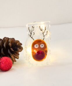 Festive reindeer decoration with lights alongside pinecones and a red ornament on a white background.