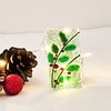 Decorative glass with holly design, surrounded by pinecones and lights on a white background.