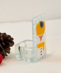 Glass snowman decoration with pinecones and a red glitter bauble on a white surface.