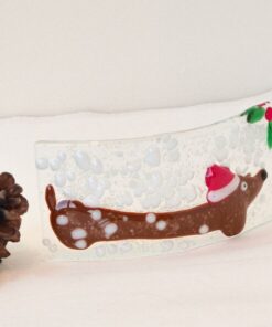 Festive glass ornament with a reindeer, Santa hat, pine cones, and a red bauble on a white background.