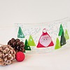 Curved glass art with a Santa figure and green trees, surrounded by pinecones and a red ornament on a white surface.