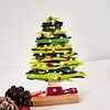 Glass Christmas tree with red and white ornaments, pinecones, and a red bauble on a white surface.