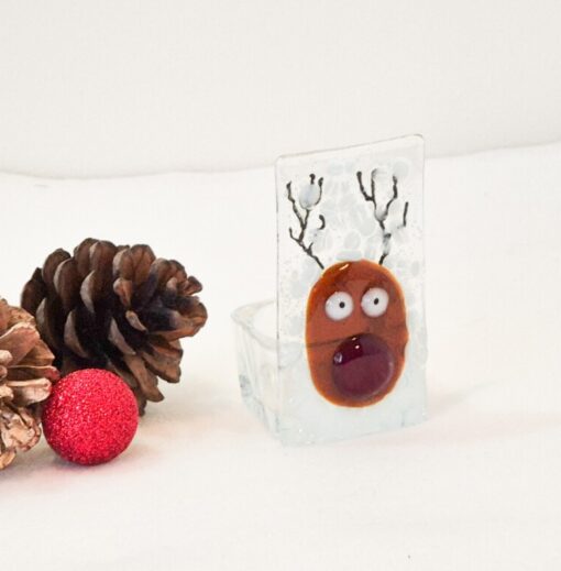 Festive glass reindeer ornament with pinecones and a red glitter ball on a white background.