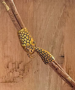 Gold snake-shaped clasp on a beige cork bracelet against a wooden background.