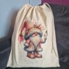 Drawstring bag with a festive gnome design holding a Christmas ornament, featuring a red hat and fur-trimmed outfit.