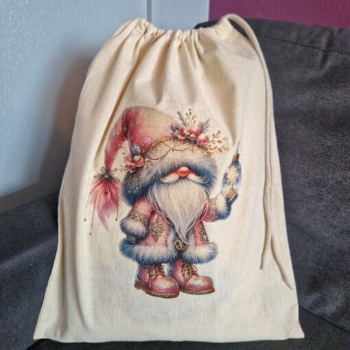 Drawstring bag with a festive gnome design holding a Christmas ornament, featuring a red hat and fur-trimmed outfit.