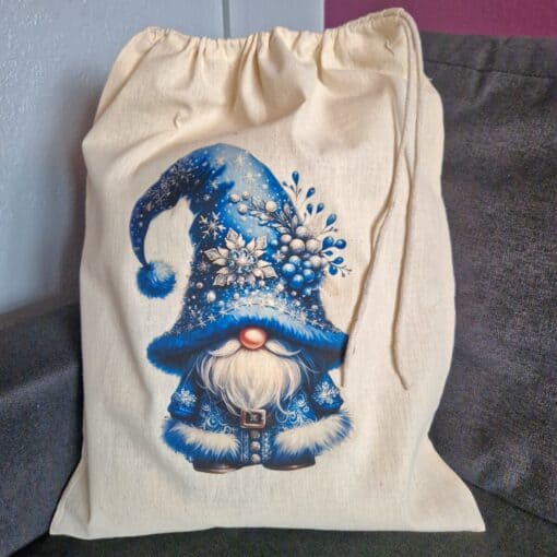 Beige drawstring bag featuring a festive gnome with a blue winter hat adorned with snowflakes and a pom-pom.