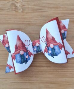 White hair bow with red trim featuring gnome designs holding pitchforks, placed on a wooden surface.