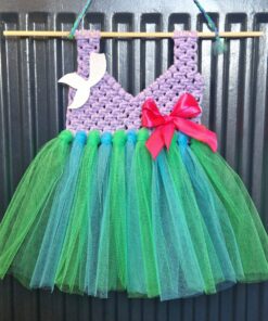 Handmade fairy dress with a purple crochet bodice, green tulle skirt, red bow, and white bird decoration, hanging on a rod.