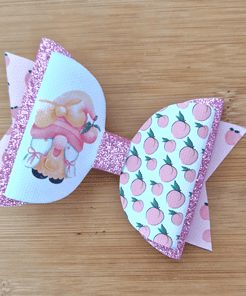 Pink and white decorative bow with glitter and peach patterns, featuring an illustration of a character on a wooden background.