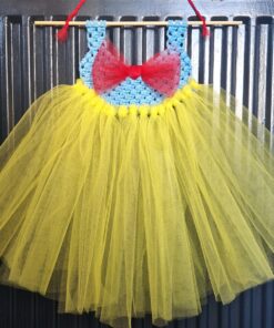 Handmade yellow tulle dress with a blue crocheted bodice and red bow, hanging on a black background.