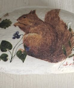 Painted rock with a squirrel and flowers beside a green ruler.