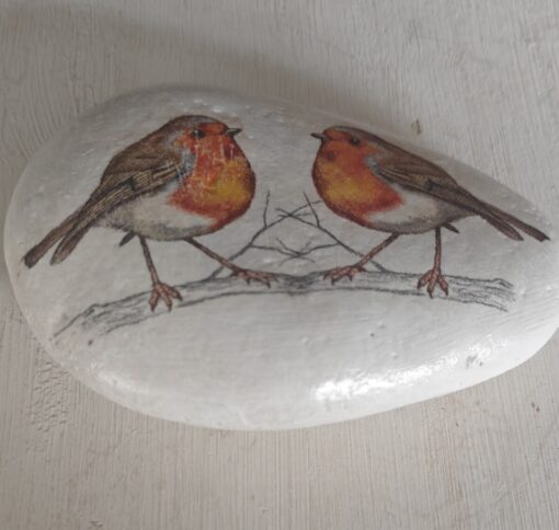 Hand-painted rock featuring two robins perched on a branch against a white background.