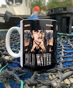 Mug on a net with an edgy black and white portrait and the text "Cold Water" outdoors near boats.