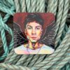 Colorful portrait of a person with angel wings on a coaster, placed on coiled ropes.