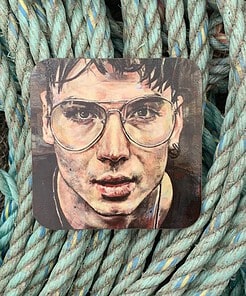 Artwork of a person with glasses on a square coaster, placed on intertwined ropes in blue and teal tones.