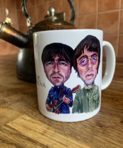 White mug with Oasis cartoon illustrations of two men, one holding a guitar, on a wooden counter beside a vintage kettle.