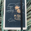 Notebook cover with illustration of a man, text "Some people know me as HOPE," and the name "Ren," against rope background.