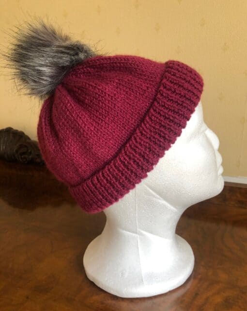 Hand knitted hat in a gorgeous plum colour. The synthetic pom pom can be detached for ease of washing. Sized as medium but will fit most adults.